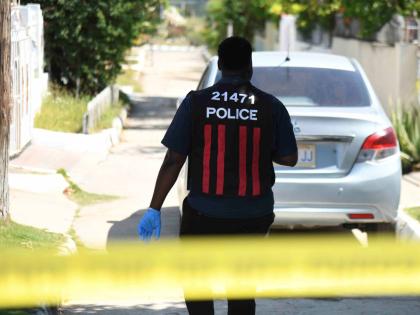A policeman approaches the house on Marlin Way in Braeton, Portmore in St Catherine yesterday, where a woman and her daughter were reportedly attacked by a man believed to be of unsound mind. The daughter was rushed to the hospital while the mother died in