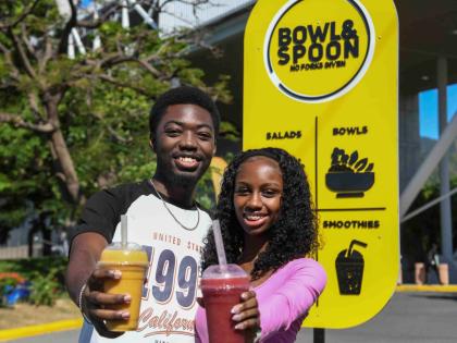 Third-year banking and finance students Amani Christie and Esther-Elizabeth McKenzie enjoy the immunity boost and tropical recharge, respectively, at Bowl and Spoon Restaurant, located at The University of the West Indies (UWI), Mona campus. 