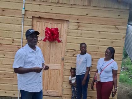 Bishop Donald McFarlane, pastor at New Foundation Christian Ministries, hands over a house to the new homeowner, Nickeisha Lewis, who was accompanied by one of her children, Shantary Thomas, and her mother, Violet Bailey.