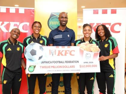 
Reggae Girlz Deneisha Blackwood (left), Allyson Swaby (second left), Kameron Simmonds(second right), and Atlanta Primus (right) flank KFC Jamaica marketing manager, Andrei Roper, who displays a cheque for $12 million, which represents the first instalment