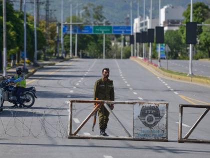 A police officer stands guard at a checkpoint on a barricaded road to ensure security ahead of the second round of the US Iran officials talks, in Islamabad, Pakistan, Sunday, April 19, 2026. (AP Photo/M.A. Sheikh)