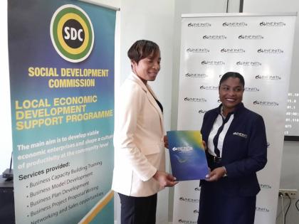 Kenyah Adamson (right), manager of the Lucea branch of the Infiniti Cooperative Credit Union Jamaica Limited, presents documents related to the entrepreneurship programme to Tova Trench-Anderson, the parish manager for the Hanover branch of the Social Deve