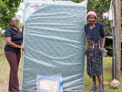 Wendy Robertson (left), corporate affairs and communication manager at the Betting, Gaming and Lotteries Commission, donates a mattress and tarpaulin to a grateful Amy Blagrove as part of hurricane supplies to the elderly and indigent in communities of eas
