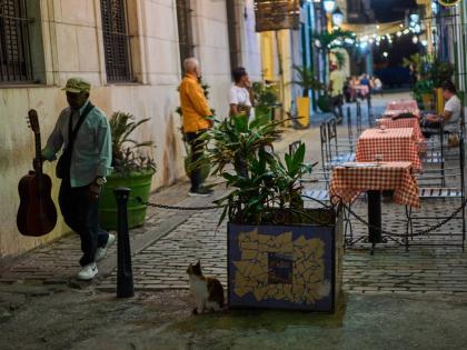 A street musician walks past a restaurant in Havana.