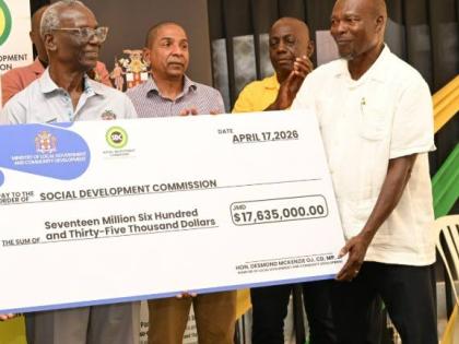 Minister of Local Government and Community Development, Desmond McKenzie (left), makes a symbolic handover of a cheque under the Government's Community Church Clean-Up and Restoration Initiative that was accepted by Reverend Othniel Watson (right) of the M