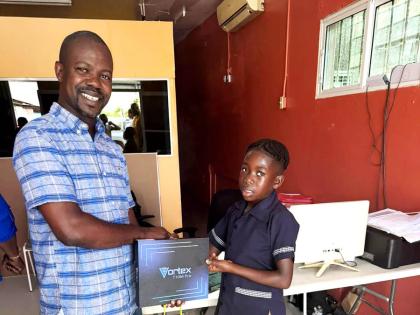 Central St Mary Member of Parliament Omar Newell presents one of 10 tablets donated by the Universal Service Fund to grade‑five student Jaleel Watson of Port Maria Primary School. 