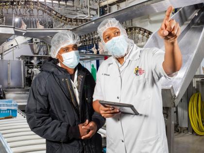 Chadwick Galloway (right), processing plant manager at The Best Dressed Chicken consults with Chad Joseph Francis, team leader/machine operator at the company’s facilties. 