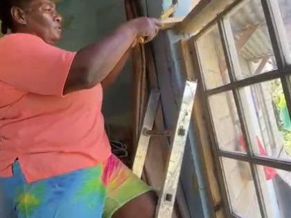Janette Cameron, a resident of Canaan, St James, works on repairing a damaged window at her house, which suffered significant damage during Hurricane Melissa on October 28 last year and has still not been fully repaired since then.