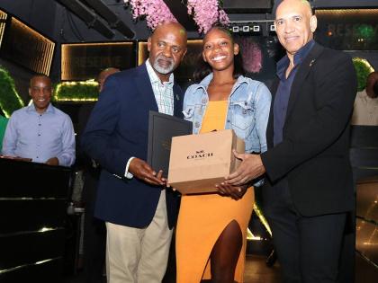 Jamaica’s Ambassador to the United States, Major General (Ret’d) Antony Anderson (right), and Team Jamaica Bickle President and CEO Irwine Clare Sr present sprint standout Shanoya Douglas of Holland High with a gift during Team Jamaica Bickle’s annua