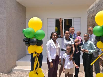 Prime Minister, Dr Andrew Holness (centre), looks on as New Social Housing Programme beneficiary Andrea Burke (second left) shows off the keys to her new home during the handover ceremony at 43 Rosemary Lane, Kingston on August 4. They are joined by (from 