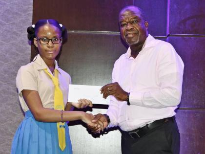 Rickaysia Powell accepts her grant from Moon Palace Vice-President Clifton Reader. Powell, a graduate of Priory Primary School in St Ann, will begin studies at Iona High School in September.