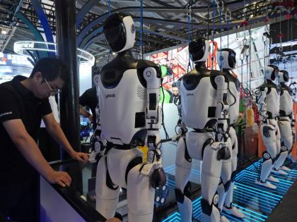 AP
A worker reacts near a line of humanoid robots displayed at the World AI Conference in Shanghai on Friday, July 17.  