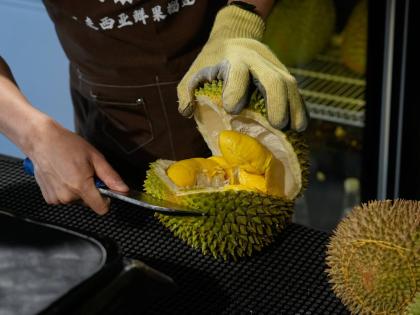 A worker opens durian fruits imported from Malaysia to pack and deliver for customers at a shop in Beijing, China.