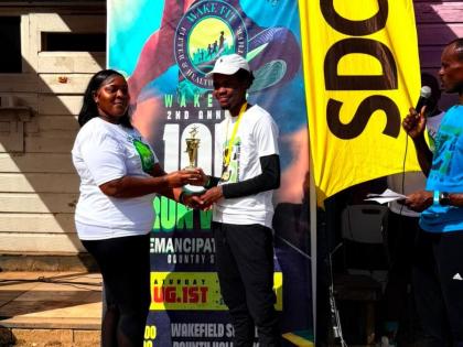 Tashalee Billings, committee member of Wake-Fit 10K Run/Walk, presents winner of the 10K Run in the 17 and over category Jaheim Morrison with his trophy, following the second staging of Wake-Fit 10K Run/Walk in Wakefield, Trelawny, on Saturday, August 1.