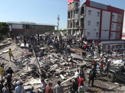 Residents and rescue workers search through the rubble of a collapsed building after an earthquake struck Cali, Colombia, Monday.
