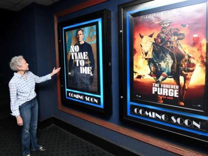 In this September 17, 2021 photo, Melanie Graham, marketing manager and director of Palace Amusement, stands in front of show posters at the company’s Carib 5 cinema in Kingston. 