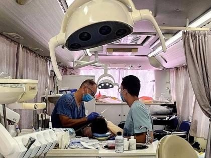 Dr Adam Szymczak (left) and his son, Justin, treat a patient inside Great Shape’s mobile dental clinic during a dental mission at the Ocho Rios High School grounds.