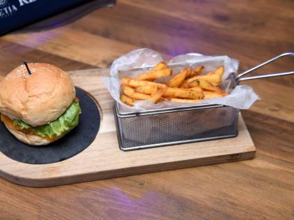 The jerk chicken burger is served with a side of fries.