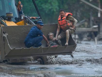 Rescuers use an earthmover to carry a victim of the flash flooding to safety along the Trishuli River in Nepal's Nuwakot district on Wednesday. - AP photo