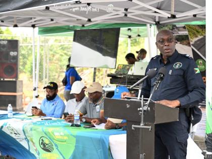 Superintendent of Police Colridge Minto (right) speaks at the opening of the Newcombe Valley to Amos Lane farm road in Pedro Plains, St Elizabeth. Seated at the head table are (from left) Richard Solomon, mayor of Black River; Karle Whyte, councillor for t