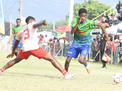 
Richardo Walker (right) from Vauxhall High School, evades a tackle from Jasai Theophilus from Mona High during their Walker Cup quarterfinal football match at the Waterhouse Stadium in Kingston yesterday.