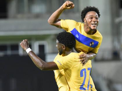 Kadean Young (right) of Racing United, celebrates with a teammate after scoring his team’s fifth goal against Molynes United in their 6-0 win at Sabina Park yesterday.