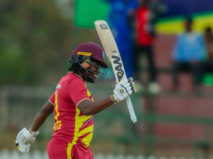 Eboni Brathwaite raises her bat in celebration of scoring a half century against Zimbabwe yesterday.