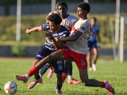 Jamaica College’s Jamone Lyle (left) tries to escape the attentions of Mona High School’s Sean Leighton during a Walker Cup semi-final match at Stadium East for which he was later deemed ineligible.