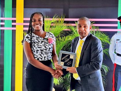 Seventeen-year-old Jamoya Seaton, the youngest among eight Clarendonians honoured at the parish’s National Heroes’ Day awards ceremony, receives her award from Clarendon Central Member of Parliament Delroy Williams.
