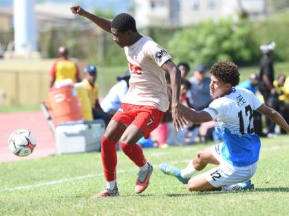 Mona High School’s Niquan Allen (left) evades a tackle from Hillel Academy’s Zachary Weir during their Manning Cup football match at the Stadium East field yesterday. Allen scored in Mona’s 8-1 win.