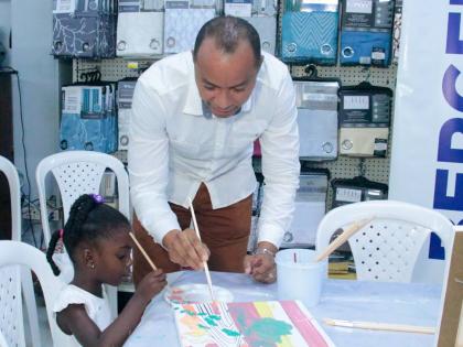 Contributed  Photos
Zhuri-Joy Crawford shows off her painting skills to the Linton Johnson, general manager of Berger Paints Jamaica Ltd, at H&L Rapid True Value on Constant Spring Road recently.