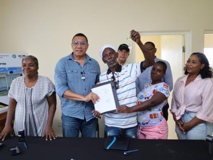 Barrington Dobson (centre), a beneficiary of the Government’s New Social Housing Programme (NSHP), accepts the contract and keys to his new three-bedroom house from Prime Minister Dr Andrew Holness (second from left) during a handover ceremony last Frida