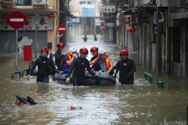 In this photo released by Xinhua News Agency, members from the local customs authority help stranded citizens to evacuate from an inundated street as Super typhoon Ragasa passed nearby Macao in southern China, September 24, 2025. (Cheong Kam Ka/Xinhua via 