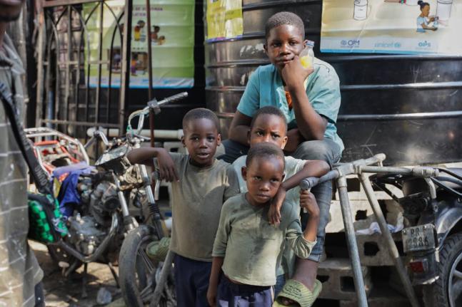 Children look at students attending school at a shelter for families displaced by gang violence in Port-au-Prince, Haiti.