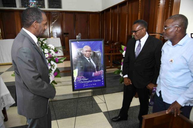 Neville Robinson (left), Trevor Scott (centre) and Lionel Dillon, members of Kingston College’s Class of 1981, look at a portrait of their late batchmate, Professor Christopher Charles, during a thanksgiving service for his life held yesterday at the Uni