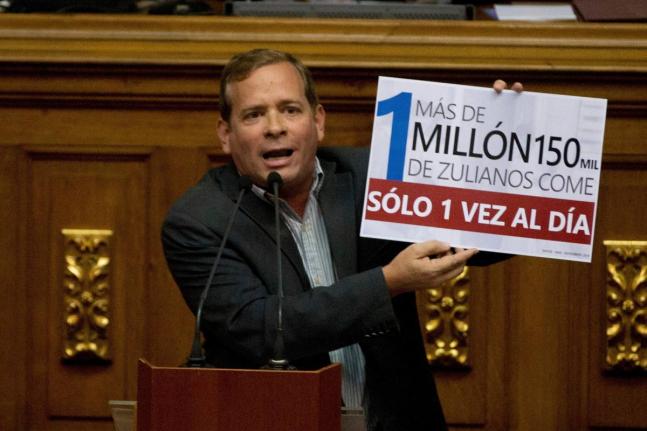  Opposition lawmaker Juan Pablo Guanipa displays a sign that reads in Spanish "More than a million residents of Zulia State eat only once a day" during an intervention against Venezuela's President Nicolas Maduro at National Assembly, in Caracas, Venezuela