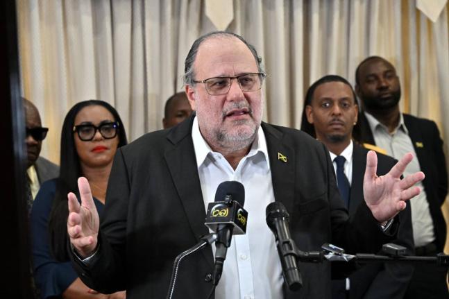 Surrounded by members of his team, Opposition Leader Mark Golding speaking at a press conference at the Office of the Leader of the Opposition on West Kings House Road in St Andrew on Tuesday.