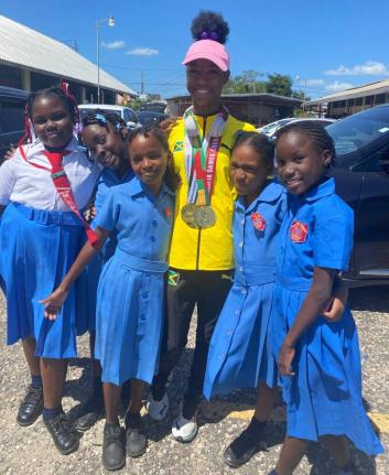 Foga Road High’s Shameika McLean (pink cap) with students from her former school, May Pen Primary, during a parade through the streets of the parish capital yesterday to celebrate the achievements of  Foga Road’s athletes at the ISSA/GraceKennedy Boys 