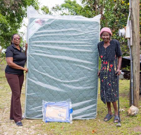 Wendy Robertson (left), corporate affairs and communication manager at the Betting, Gaming and Lotteries Commission, donates a mattress and tarpaulin to a grateful Amy Blagrove as part of hurricane supplies to the elderly and indigent in communities of eas