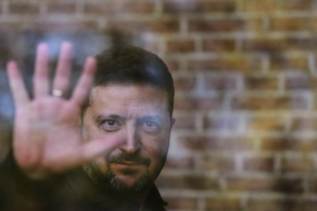 Ukraine’s President Volodymyr Zelenskyy waves from behind a glass window after he received the Freedom Medal of the International Four Freedoms Award during a ceremony in Middelburg, Netherlands, Thursday, April 16. 