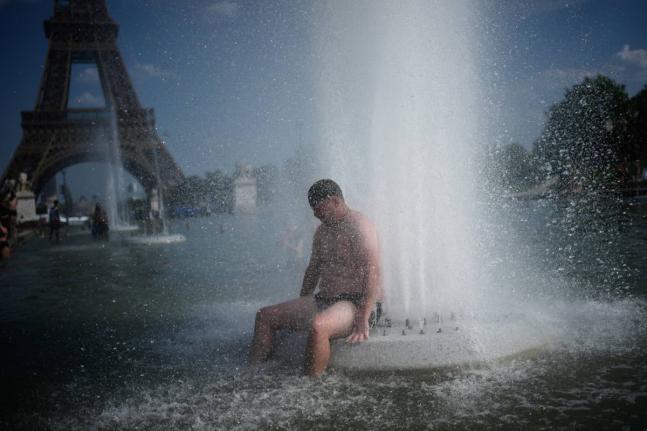 FILE - A person cools off at Trocadero fountain near the Eiffel Tower during a heat wave in Paris, on June 24, 2026. (AP Photo/Christophe Ena, File)
