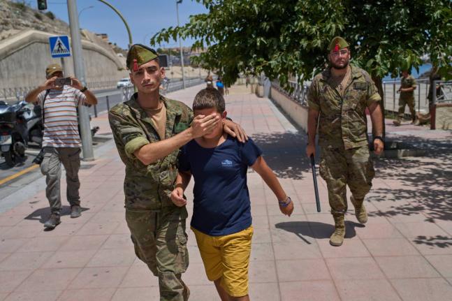 A 12-year-old unaccompanied minor who crossed into Spain is escorted by a Spanish soldier to the Spain-Morocco border from the Spanish enclave of Ceuta, Monday.