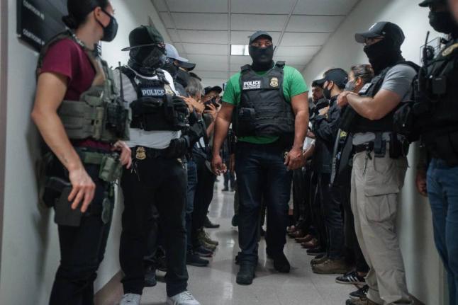 Masked federal agents wait outside an immigration courtroom, July 8, 2025, in New York.