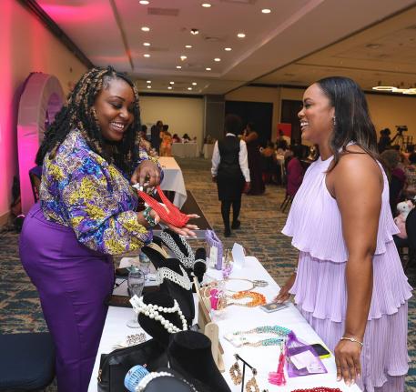 We Inspire Women exhibitor Shauna Kaye Whitter (left) of Kay Anne’s Kollection engages with Charissa Clemetson during the 2023 event. 