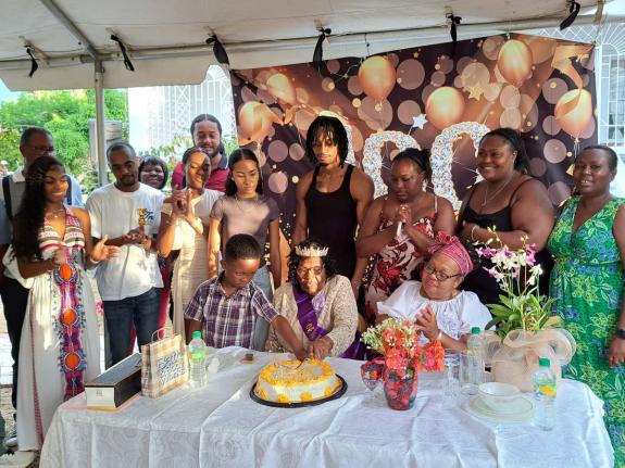 Adele Warner (seated centre) cuts into her birthday cake alongside one of her grandchildren as other members of her family look on during a celebration of her 100th birthday at her home in Goodwill, St James, on Sunday. The celebration was held ahead of Wa
