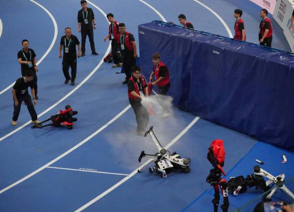 Officials extinguish the fire to a Humanoid robot after hitting the barrier at the end of the 100m race during the World Humanoid Robot Games in Beijing, China, on Tuesday. - AP photo