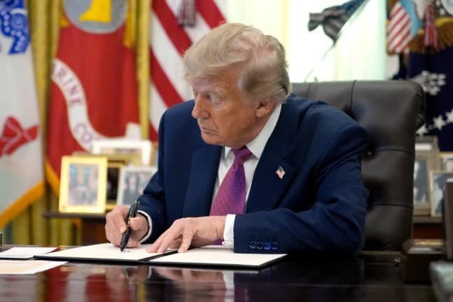 President Donald Trump signs an executive order in the Oval Office of the White House, Thursday.