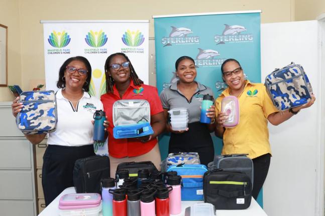 Representatives of Sterling Asset Management Ltd. and Maxfield Park Children’s Home showcase a selection of the donated items, including lunch boxes, insulated water bottles and food containers, provided to support the children of the home ahead of the n