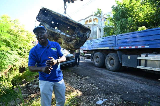Workmen from the National Solid Waste Management Authority (NSWMA) remove a derelict vehicle in Norwood, St James, during a clean-up operation on October 29.