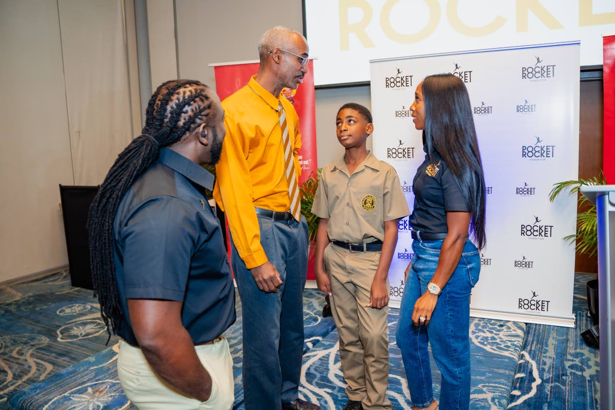 Dr Jermaine McCalpin (left), executive director of the Pocket Rocket Foundation, and Shelly-Ann Fraser-Pryce, founder of the foundation, listen attentively as Cary Fletcher (second left) shares the accomplishments of his son, Michael Fletcher.
